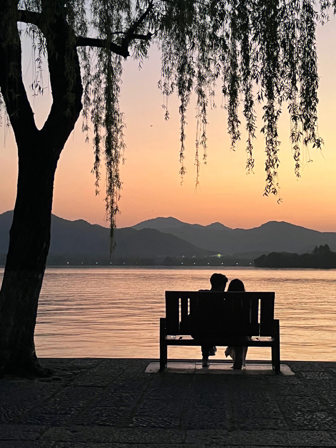 西湖边等落日长椅上的情侣正在用粤语唱张国荣的《有心人》和朋友七嘴
